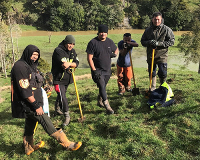 Image of several men holding shovels and standing in a line