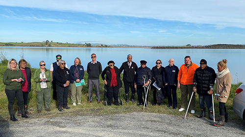 Image of a group of people standing next to a lake edge