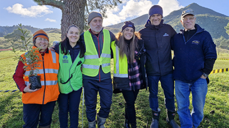 Image of several people standing together in front of a tree